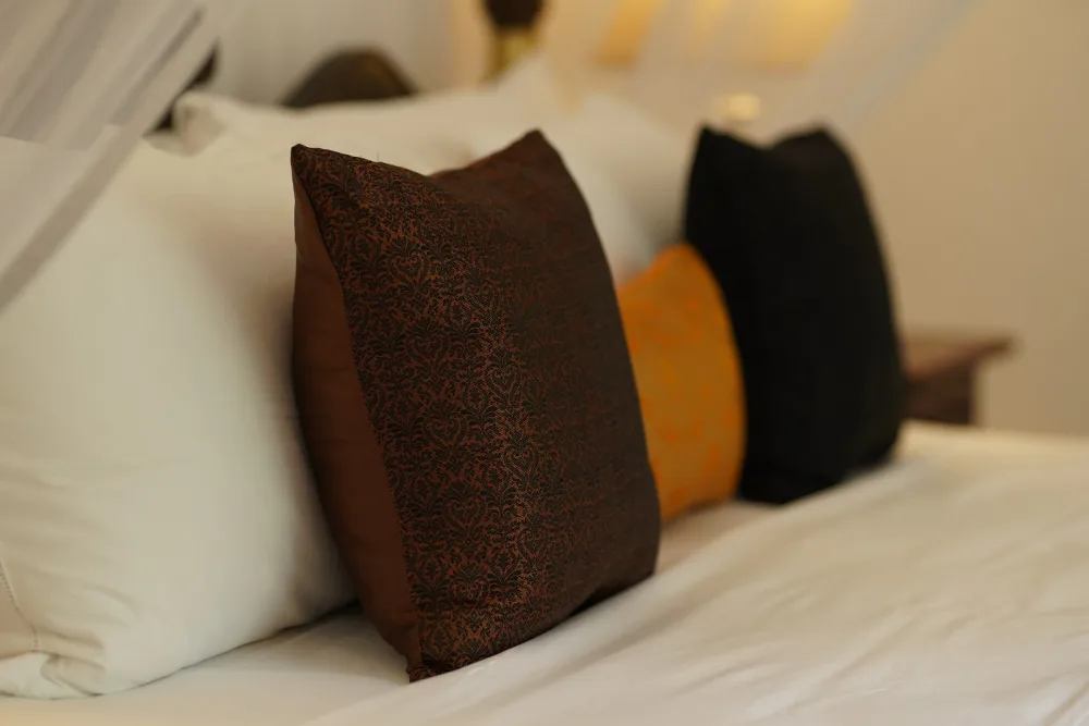 A neatly made bed with white sheets and pillows in the black raja bedroom of Adigar's manor.