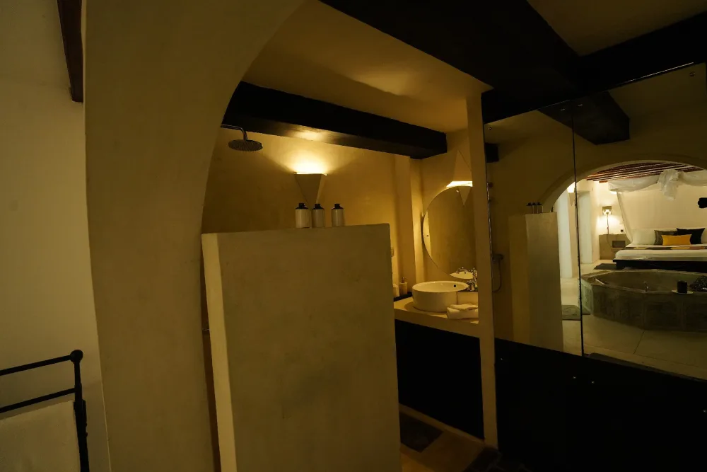 The bathroom in the Black Raja bedroom of Adigar's manor, featuring a sink and a mirror.