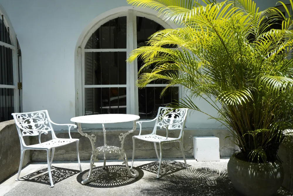 A white table and chairs set in Adigar's Manor, showcasing a simple and elegant dining arrangement.