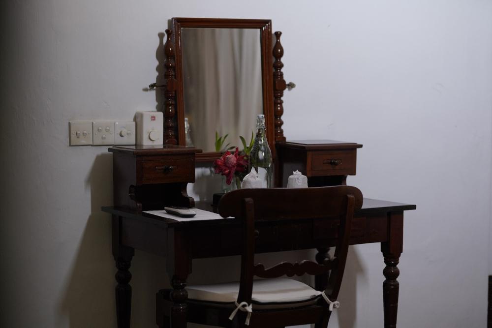A small table with a chair and a mirror in the Connelian room of Adigar's manor.