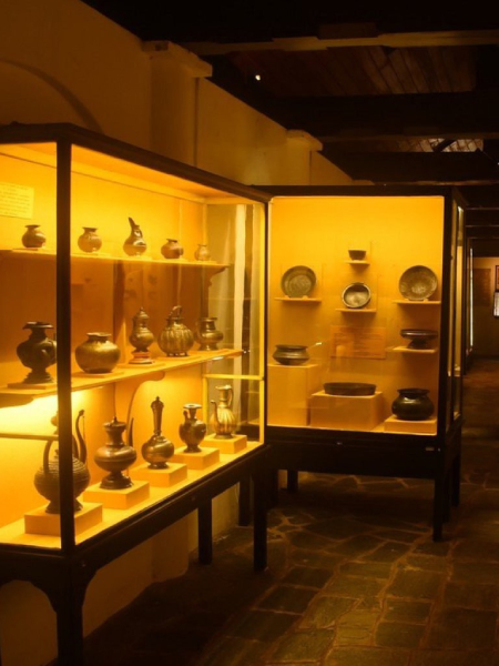 A collection of vases displayed in a case at Kandy Museum, illustrating cultural artistry and design diversity.
