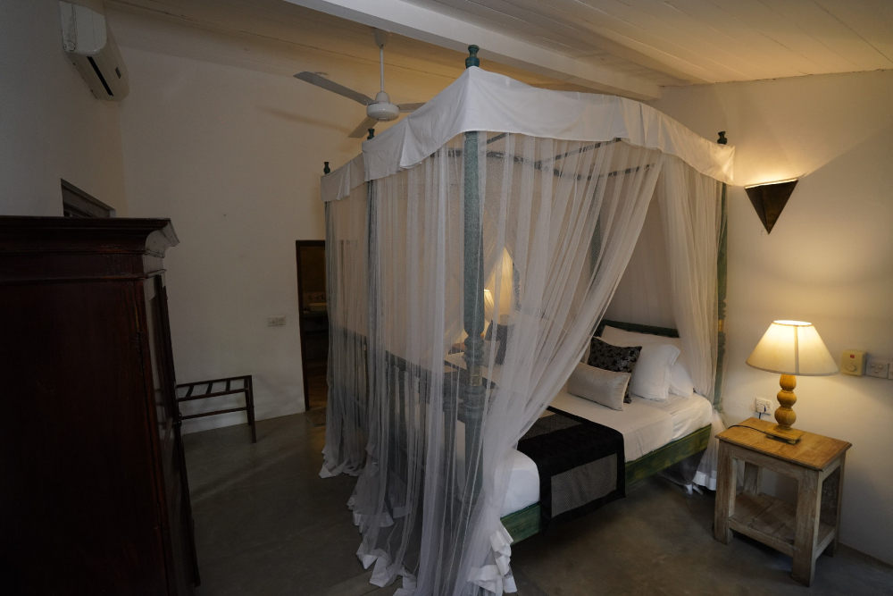 The canopy bed in the pioneer room of Adigar's manor, highlighting its historical significance and elegant design.