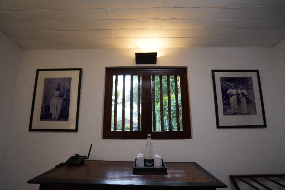 A pioneer room in Adigar's Manor featuring a desk and two framed pictures on the wall.