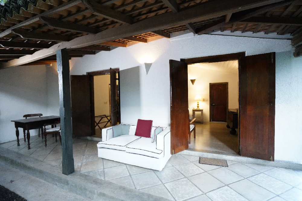 Interior of Adigar's manor with a couch and table facing a door, creating a cozy atmosphere
