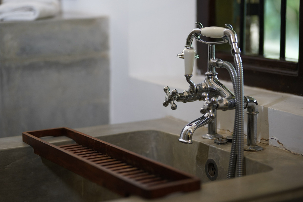A wooden tray on a bath tub with a faucet, located in the Red Spot Duke room of Adigar's Manor.