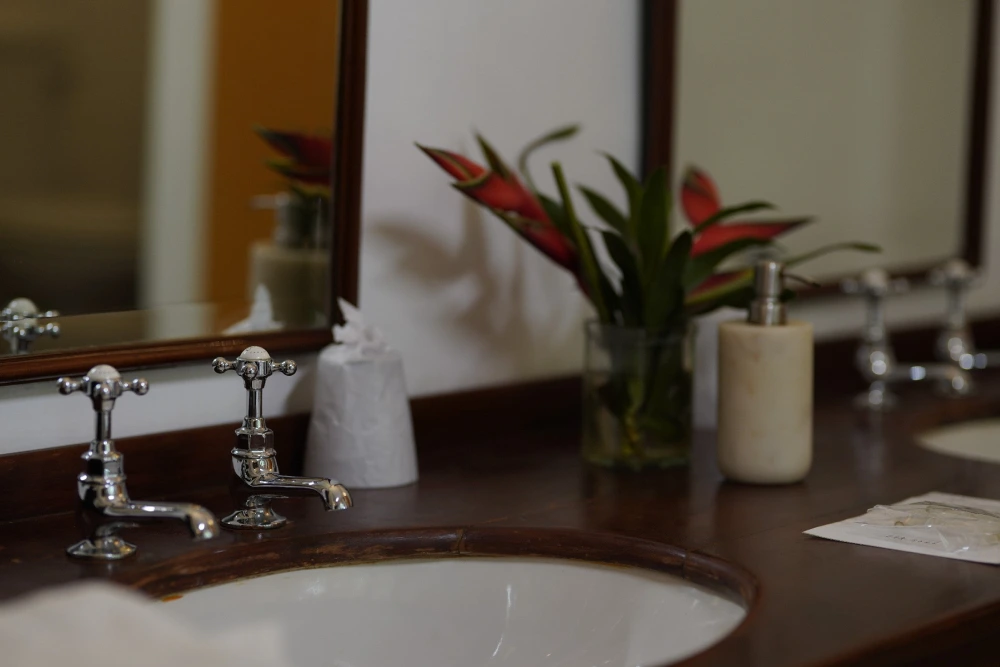 A spacious bathroom with a mirror and dual sinks, situated in the sunbeam bedroom of Adigar's manor.