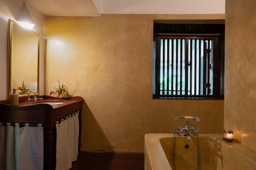Cornelian Room bathroom featuring elegant bathtub, warm ambient lighting, rustic wooden vanity, and serene luxury interior