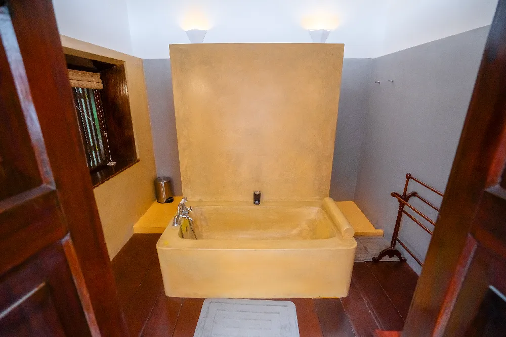 Cornelian Room bathroom with spacious soaking bathtub, warm ambient lighting, wooden accents, and minimalist luxury design