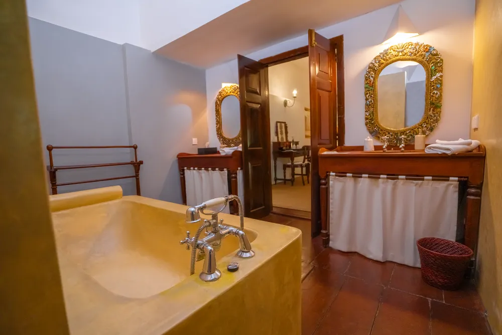 Cornelian Room bathroom with luxury soaking tub, ornate vintage mirrors, warm lighting, and elegant colonial-style interiors