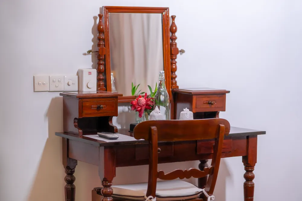 Cornelian Room wooden vanity table with classic mirror, chair, fresh flowers, and elegant colonial-style décor