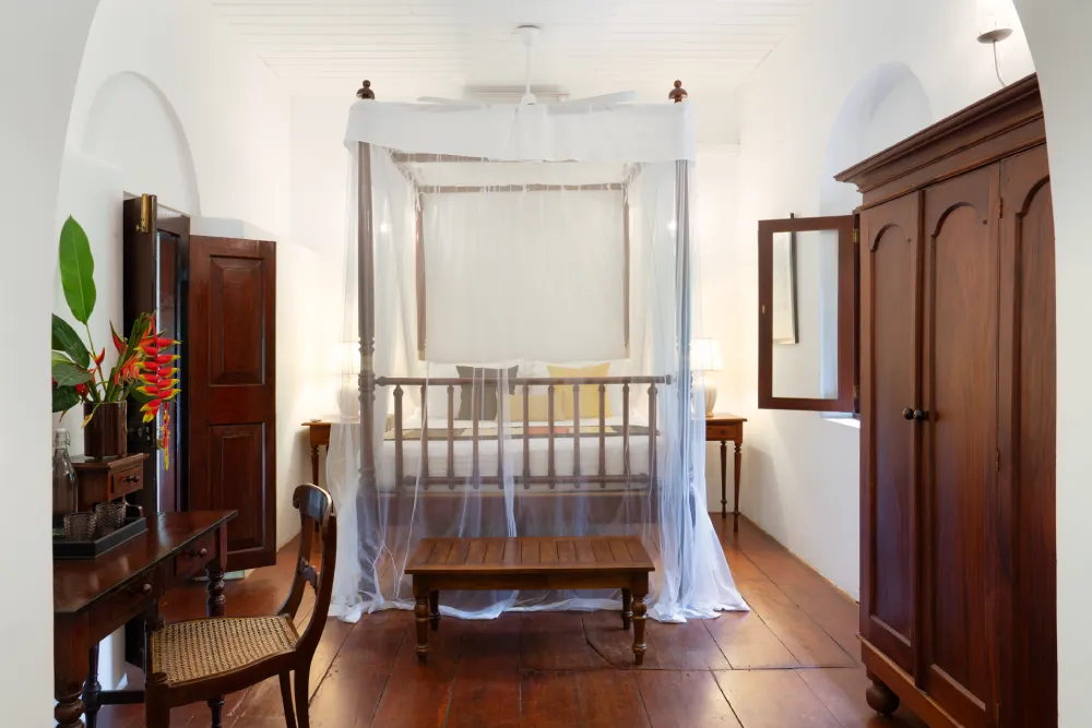 Lime Butterfly Room with elegant four-poster canopy bed, polished wooden floors, antique wardrobe, and bright colonial-style interiors