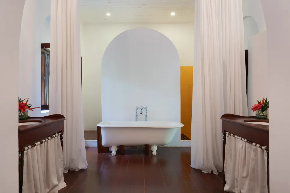 Lime Butterfly Room bathroom with freestanding bathtub, elegant white curtains, wooden vanities, and bright colonial-style luxury interiors