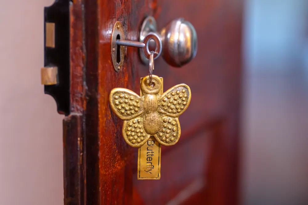 Close-up of decorative butterfly room key hanging from a vintage wooden door lock in the Lime Butterfly Room