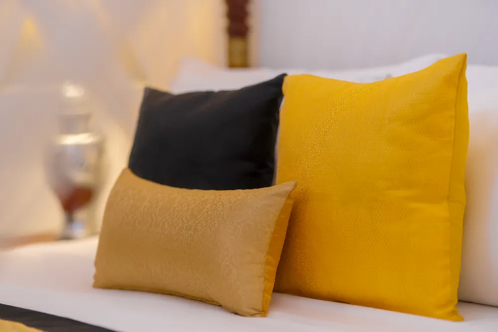 Close-up of elegant decorative cushions in the Lime Butterfly Room featuring warm golden tones and luxury bedding details