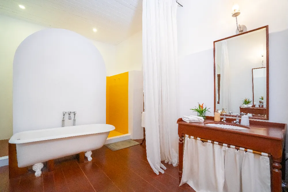 Lime Butterfly Room bathroom with freestanding bathtub, elegant wooden vanity, soft white curtains, and bright luxury colonial-style interiors