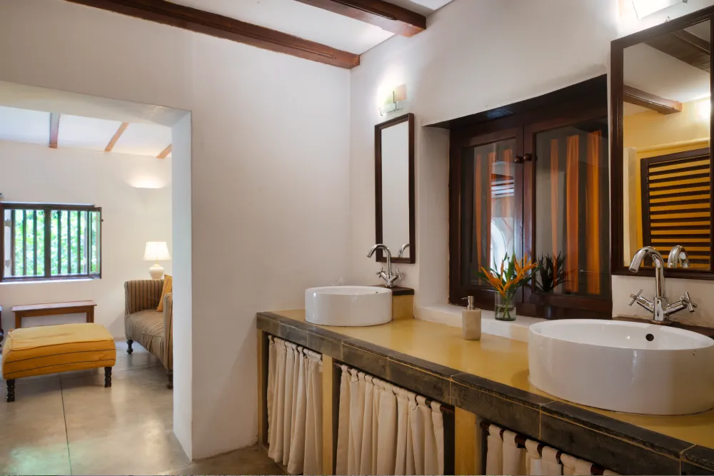 Monkey Puzzle Room bathroom with twin vessel sinks, warm wooden accents, and an open layout leading to the bedroom suite