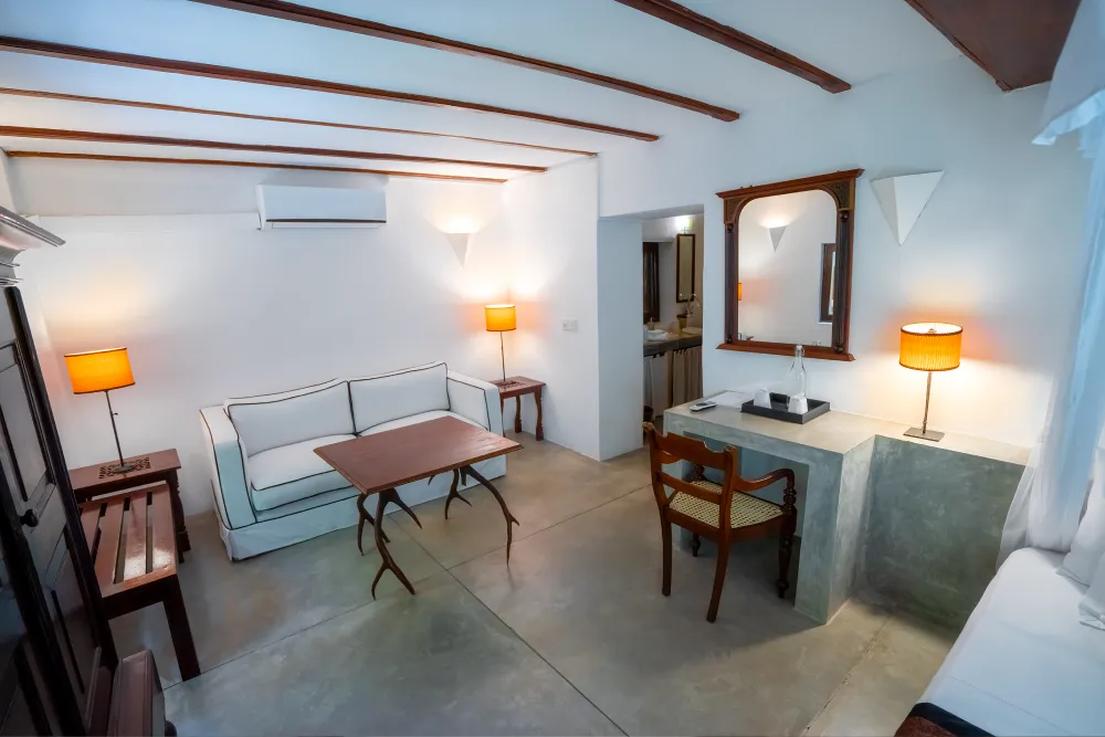 Spacious Monkey Puzzle Room lounge area with writing desk, cozy seating, warm lighting, and colonial-inspired interior design