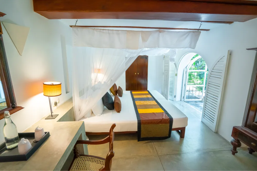 Monkey Puzzle Room with elegant canopy bed, soft ambient lighting, colonial-style interiors, and private balcony access
