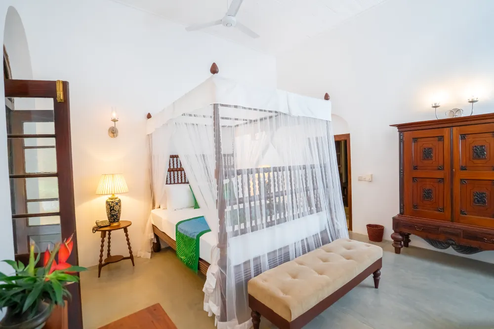 Spacious Peacock Royal Room with elegant four-poster canopy bed, antique wooden furniture, and soft ambient lighting