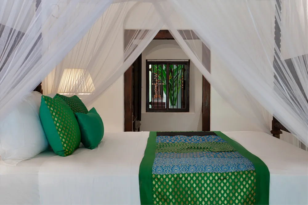 Elegant Peacock Royal Room featuring a canopy bed with flowing white drapes, emerald green cushions, and luxurious traditional décor