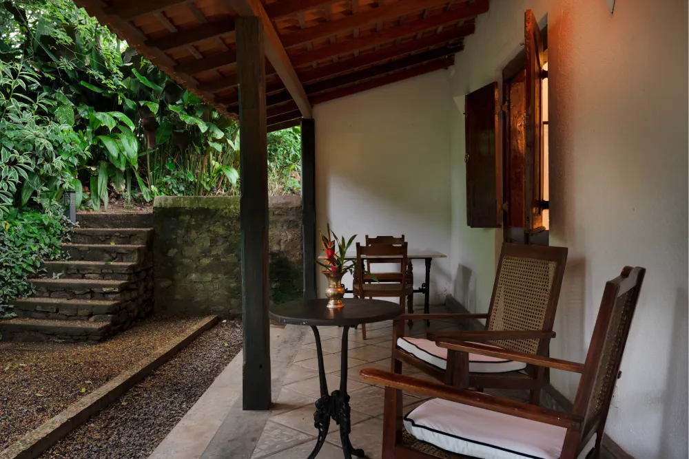 Private outdoor terrace of the Pioneer Room with wooden lounge chairs, tropical greenery, and peaceful garden surroundings