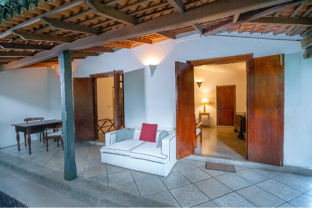 Outdoor veranda entrance to the Pioneer Room featuring colonial-style architecture, open wooden doors, lounge seating, and warm ambient lighting