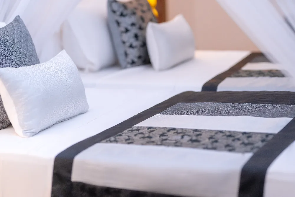 Close-up of the Pioneer Room canopy bed featuring patterned black-and-white bed runner, plush cushions, and soft white linens