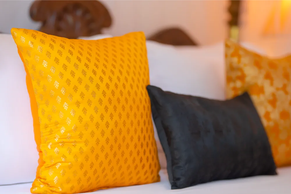 Close-up of decorative cushions on the Sunbeam Room canopy bed featuring rich golden yellow and dark accent pillows