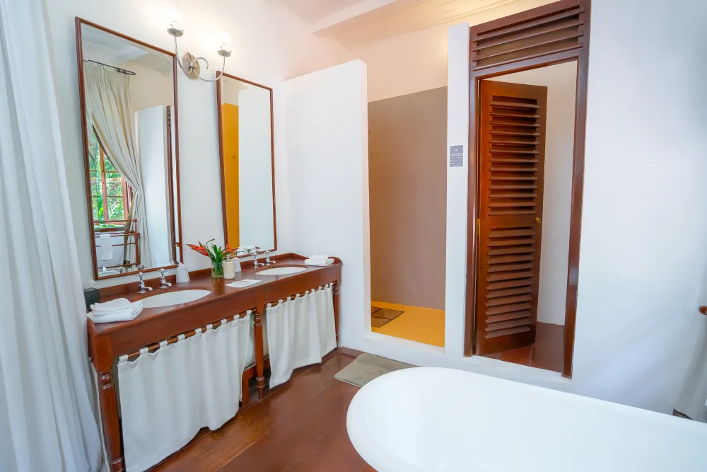 Spacious Sunbeam Room bathroom with double vanity sinks, freestanding bathtub, and walk-in shower in a bright tropical-inspired setting