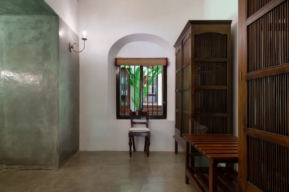 Redspot Duke Room featuring elegant wooden wardrobes, minimalist colonial interiors, polished concrete flooring, and a serene tropical courtyard view